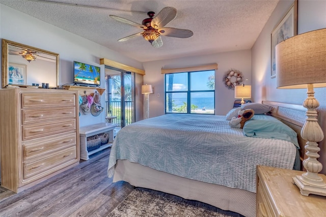 bedroom with ceiling fan, hardwood / wood-style flooring, a textured ceiling, and access to exterior