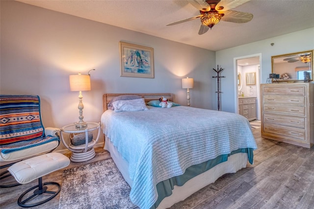 bedroom with a textured ceiling, ensuite bathroom, light wood-type flooring, and ceiling fan