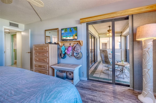 bedroom featuring ceiling fan, hardwood / wood-style flooring, access to outside, and a textured ceiling