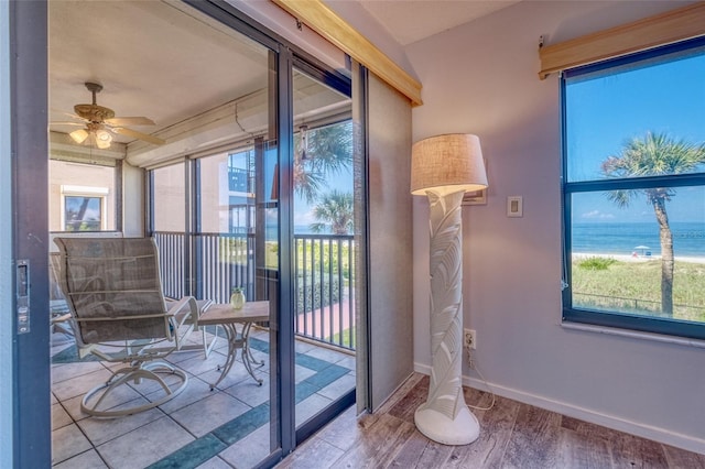 doorway to outside featuring a water view, light hardwood / wood-style floors, a wealth of natural light, and ceiling fan