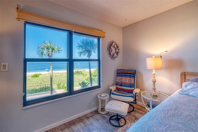 bedroom with a water view, hardwood / wood-style flooring, and a textured ceiling