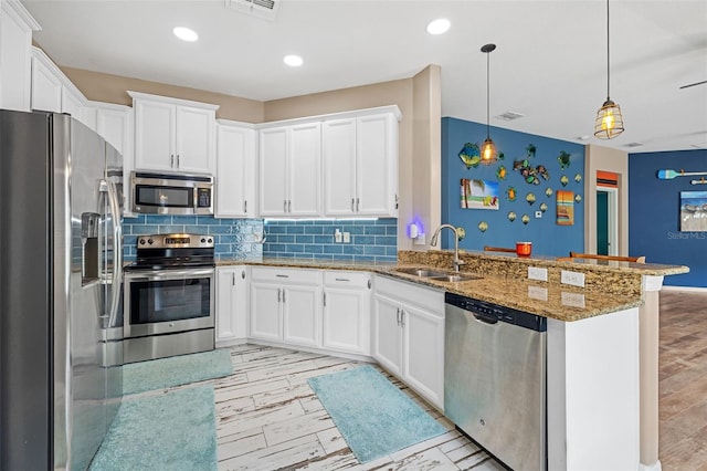 kitchen featuring white cabinetry, kitchen peninsula, stainless steel appliances, decorative light fixtures, and sink