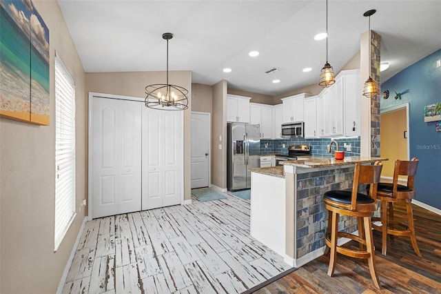 kitchen featuring stainless steel appliances, plenty of natural light, kitchen peninsula, and white cabinetry