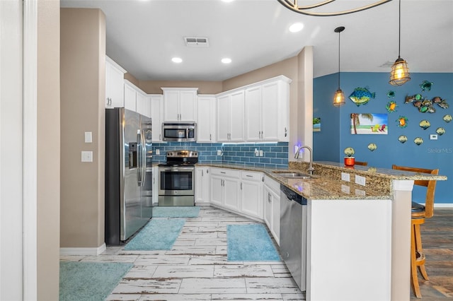 kitchen with sink, white cabinets, kitchen peninsula, a kitchen breakfast bar, and stainless steel appliances