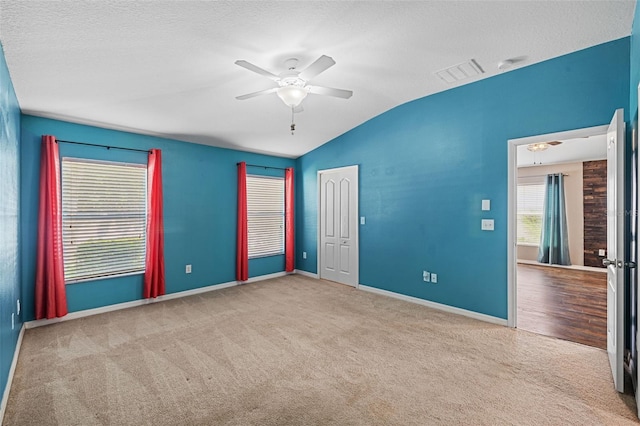 carpeted spare room featuring ceiling fan, a textured ceiling, and vaulted ceiling