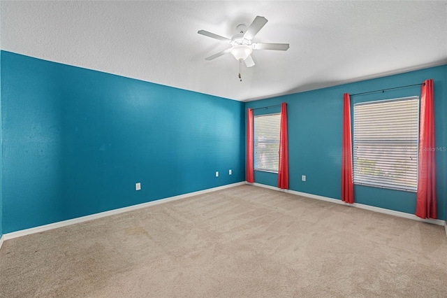 empty room featuring a textured ceiling, ceiling fan, and light colored carpet