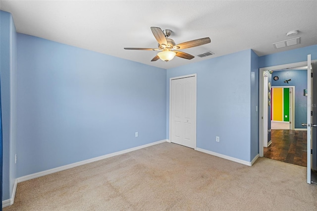 unfurnished bedroom featuring ceiling fan, light colored carpet, and a closet