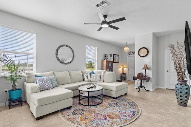 tiled living room with ceiling fan and a textured ceiling