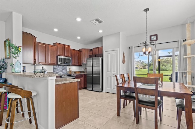 kitchen with stainless steel appliances, an inviting chandelier, kitchen peninsula, a textured ceiling, and decorative light fixtures