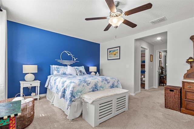 bedroom featuring a textured ceiling, ceiling fan, and light carpet