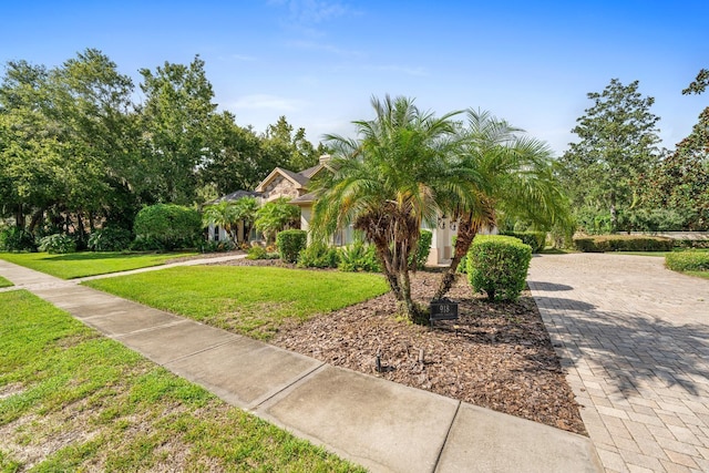 exterior space featuring a front lawn, decorative driveway, and stucco siding
