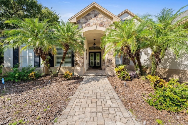 doorway to property featuring stone siding, french doors, and stucco siding