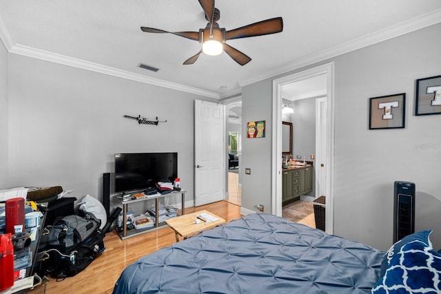bedroom with crown molding, light wood-style flooring, baseboards, visible vents, and a ceiling fan