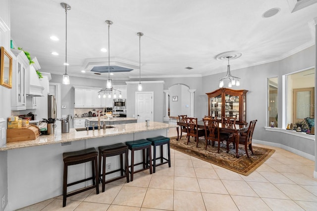 kitchen with light tile patterned flooring, stainless steel appliances, arched walkways, and a peninsula