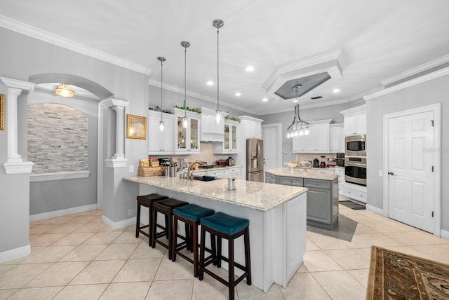 kitchen featuring light tile patterned flooring, decorative backsplash, ornamental molding, decorative columns, and appliances with stainless steel finishes
