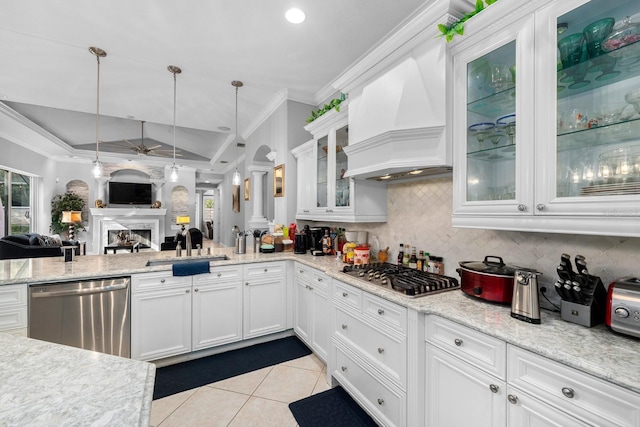 kitchen with a fireplace, ornamental molding, stainless steel appliances, a sink, and custom range hood