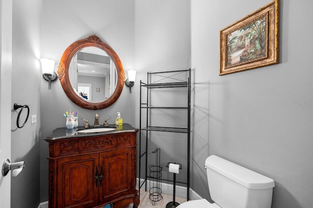 half bath with toilet, vanity, and baseboards