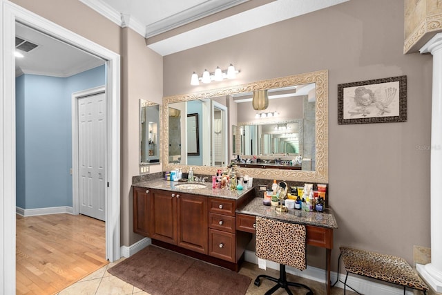 bathroom with vanity, wood finished floors, baseboards, visible vents, and ornamental molding