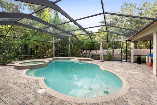 view of swimming pool featuring glass enclosure, a pool with connected hot tub, and a patio area