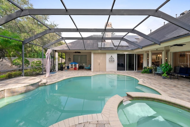 view of swimming pool with a pool with connected hot tub, glass enclosure, ceiling fan, and a patio area