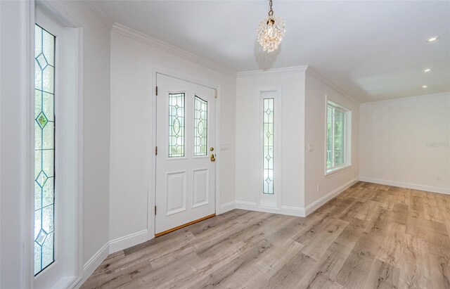 entryway with a chandelier, light hardwood / wood-style flooring, and ornamental molding