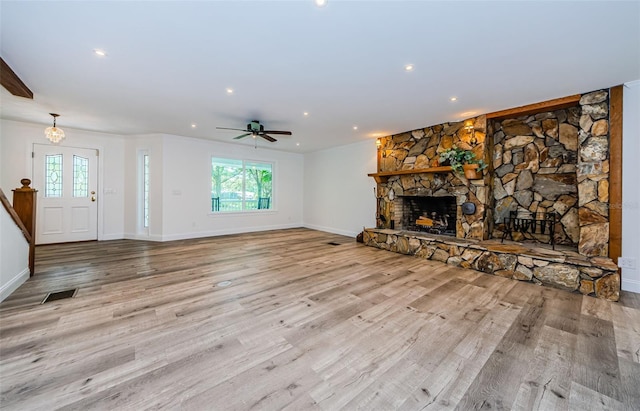 unfurnished living room with light hardwood / wood-style flooring, a stone fireplace, and ceiling fan