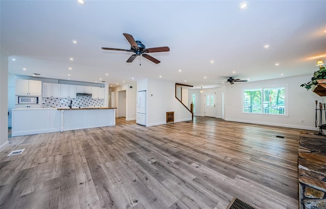 unfurnished living room featuring ceiling fan and light wood-type flooring