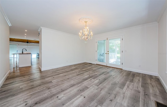 unfurnished room featuring french doors, light wood-type flooring, ornamental molding, sink, and a chandelier