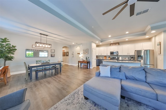 living room featuring a tray ceiling, ceiling fan, and dark wood-type flooring