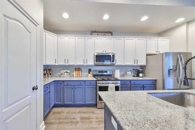 kitchen with sink, stainless steel appliances, light hardwood / wood-style floors, and white cabinetry