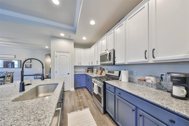 kitchen with appliances with stainless steel finishes, light hardwood / wood-style floors, white cabinets, crown molding, and sink