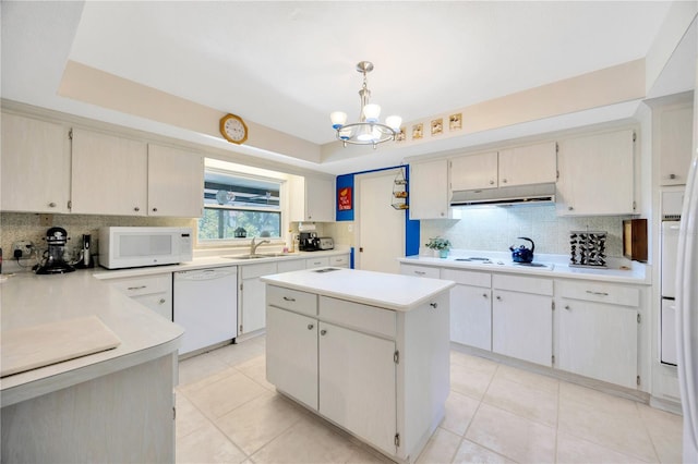 kitchen with white appliances, a center island, decorative light fixtures, sink, and a chandelier