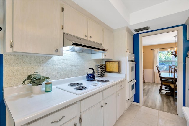 kitchen with an inviting chandelier, white appliances, light hardwood / wood-style floors, and tasteful backsplash