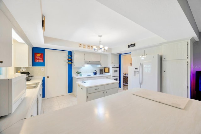 kitchen featuring pendant lighting, a center island, a notable chandelier, white appliances, and backsplash