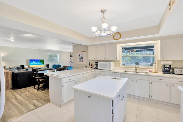 kitchen featuring pendant lighting, a center island, sink, light hardwood / wood-style flooring, and an inviting chandelier