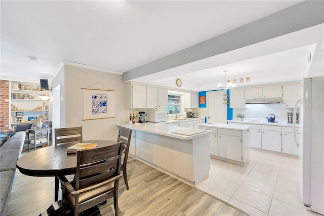 kitchen with light hardwood / wood-style floors, a center island, white cabinetry, kitchen peninsula, and white appliances