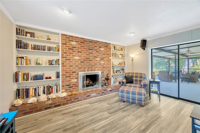 living room with ornamental molding, a fireplace, hardwood / wood-style floors, and built in features