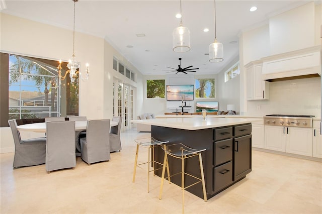 kitchen featuring stainless steel gas cooktop, open floor plan, a kitchen island, and white cabinets