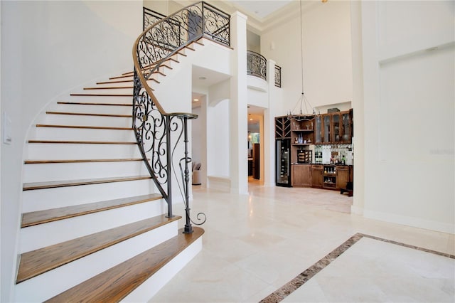 staircase featuring a high ceiling, arched walkways, baseboards, and indoor bar