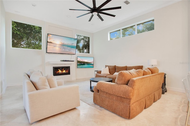 living room featuring ceiling fan, visible vents, baseboards, and a glass covered fireplace