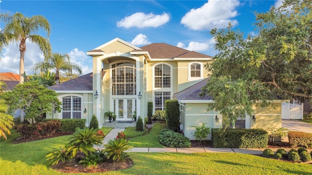 mediterranean / spanish-style home featuring a front yard, french doors, driveway, and stucco siding