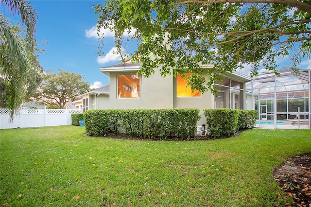 view of side of home featuring stucco siding, a lawn, fence, a fenced in pool, and a lanai