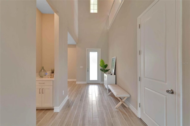 foyer entrance with light wood-type flooring and a towering ceiling