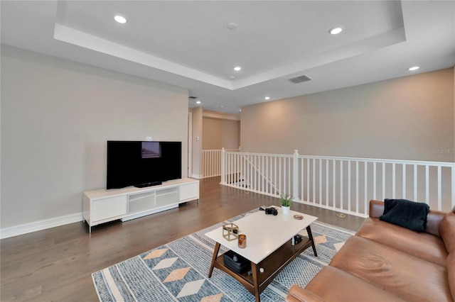 living room with a raised ceiling and dark hardwood / wood-style flooring