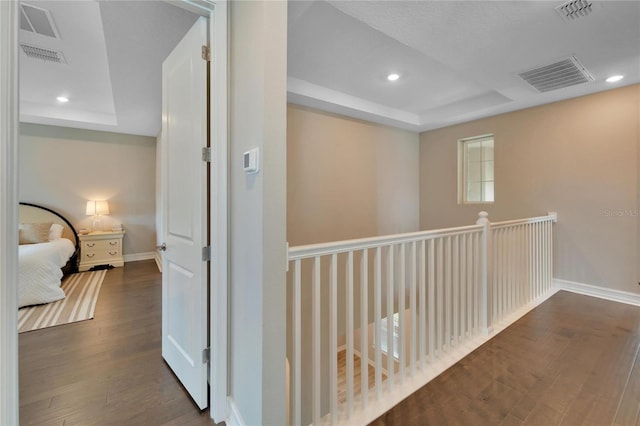 hall featuring a raised ceiling and dark hardwood / wood-style floors