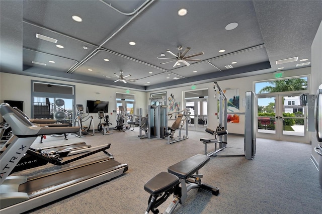 gym featuring a tray ceiling, ceiling fan, and french doors