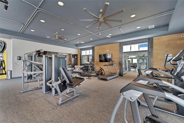 exercise room featuring ceiling fan, wooden walls, and carpet