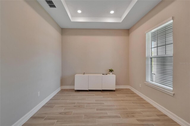 unfurnished room featuring a raised ceiling and light hardwood / wood-style flooring