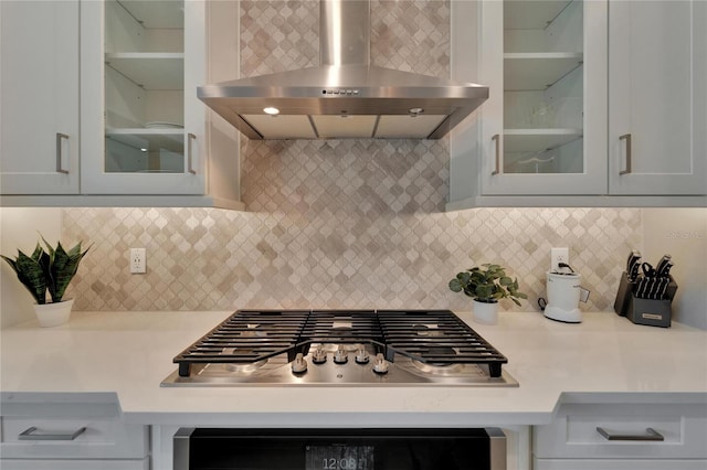 kitchen featuring stainless steel gas cooktop, wall chimney range hood, and decorative backsplash