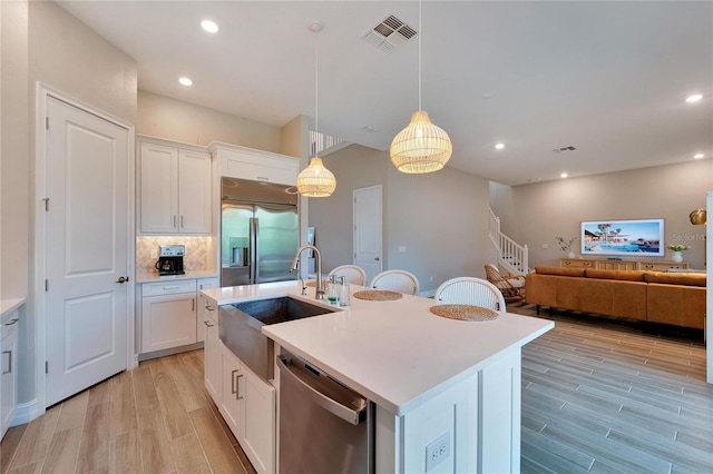 kitchen featuring white cabinetry, a center island with sink, appliances with stainless steel finishes, and sink